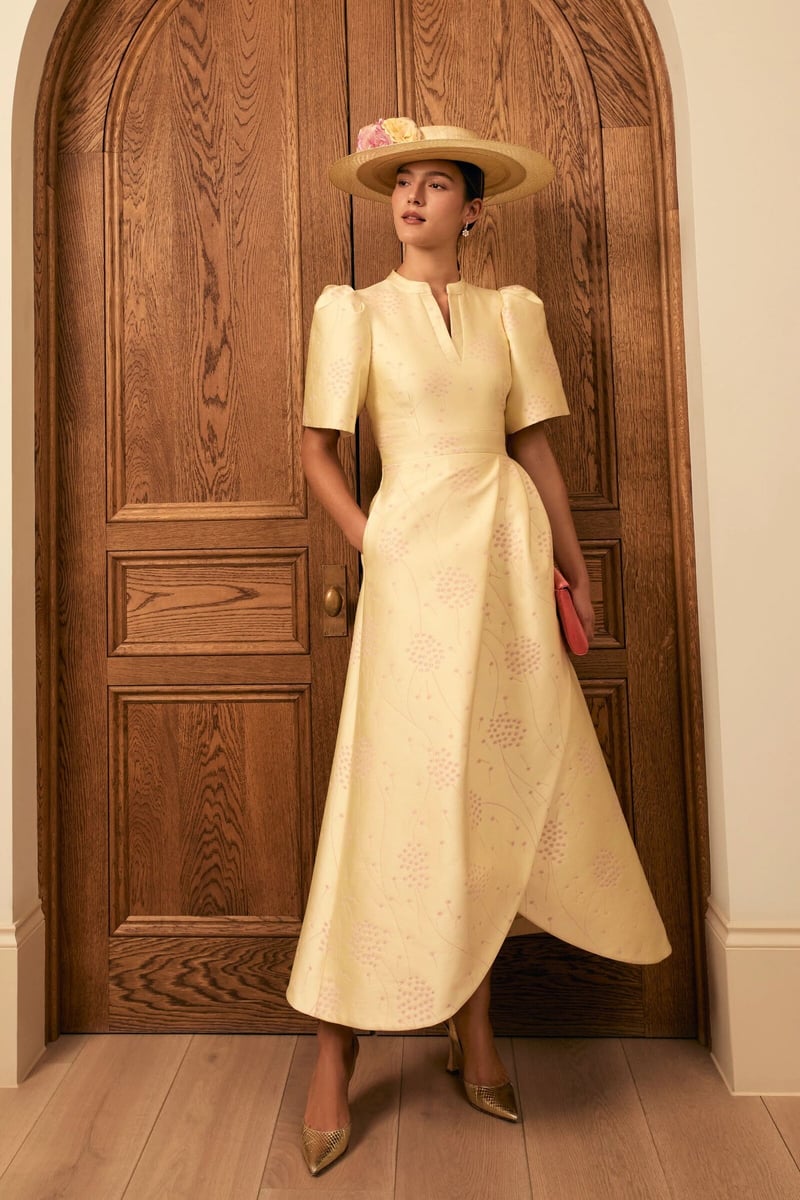 a model wears a lemon-coloured silk mother of the bride dress and matching hat.