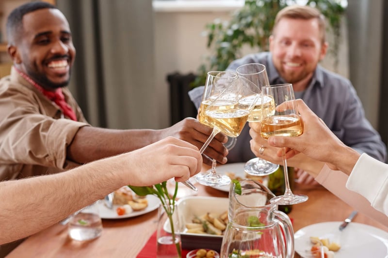a group of men on a stag do enjoying a meal, clinking wine glasses.