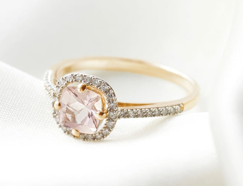 a yellow gold halo engagement ring with pink central gemstone.