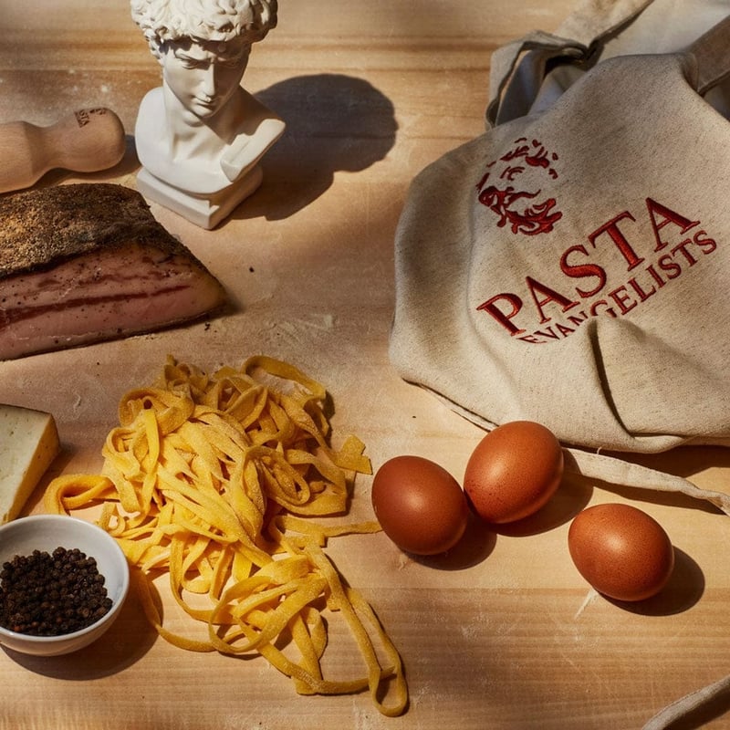 close up of a table with fresh pasta, eggs, and brand merch.
