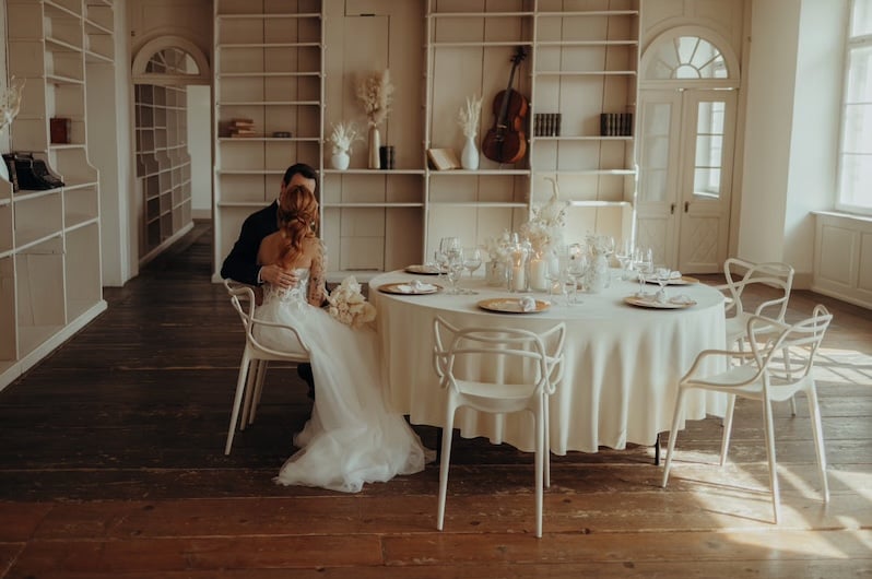 Hochzeitspaar sitzt an einem gedeckten Tisch und küsst sich