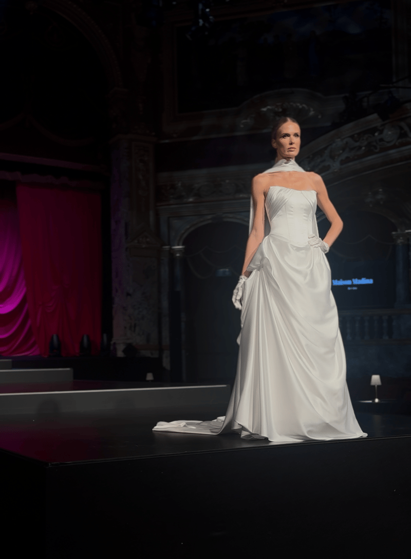 Bride on a runway in a satin corset wedding dress paired with a neck scarf and white gloves