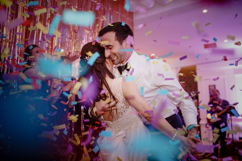 a bride and groom do their wedding first dance as confetti falls around them.