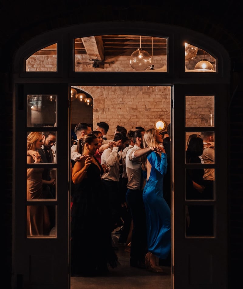 a group of guests party inside a barn wedding venue.