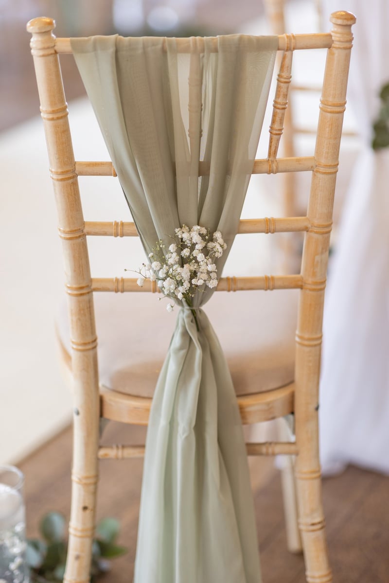 a chiavari chair with a pale green sash tied together with a sprig of gypsophila.