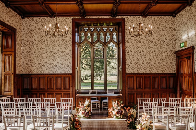 interior of a castle wedding venue set up for a ceremony with a window that has views of the grounds.