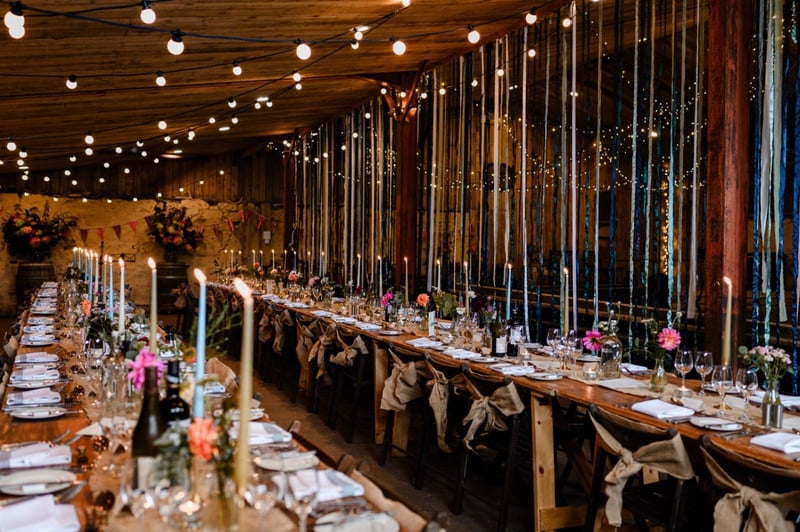interior of a barn wedding venue set up for a wedding reception in autumn, with trailing flowers hanging from the beams.