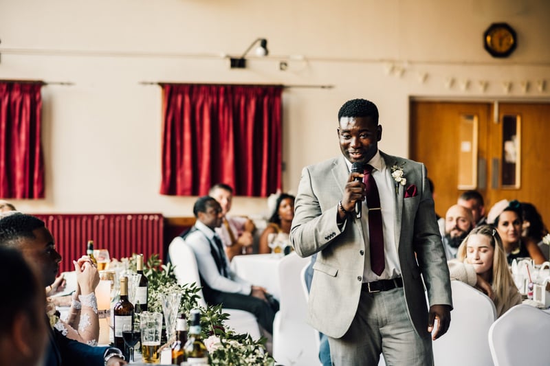 a best man walking across the room with a microphone.