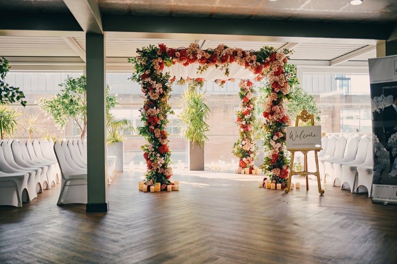 a spacious room showing a wedding welcome sign with a floral arch at the entrance.