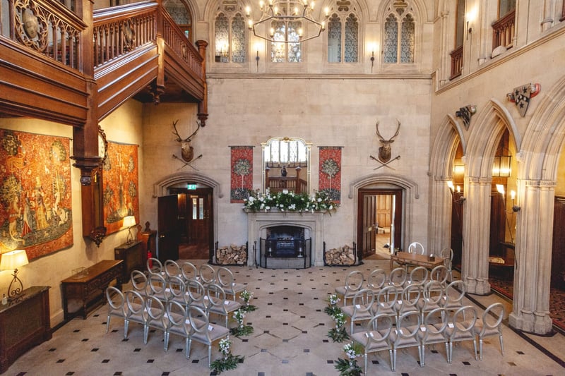 interior of a historic hall wedding venue set up for an autumnal wedding ceremony in front of a feature fireplace.