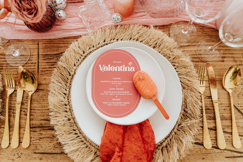 a hessian place setting with gold cutlery, orange napkin and modern pink menu personalised with the name 'Valentina'.