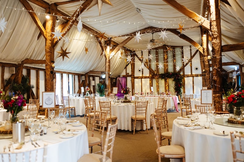 a wedding barn interior set up for a Christmas wedding reception with hanging gold stars and fairy lights.