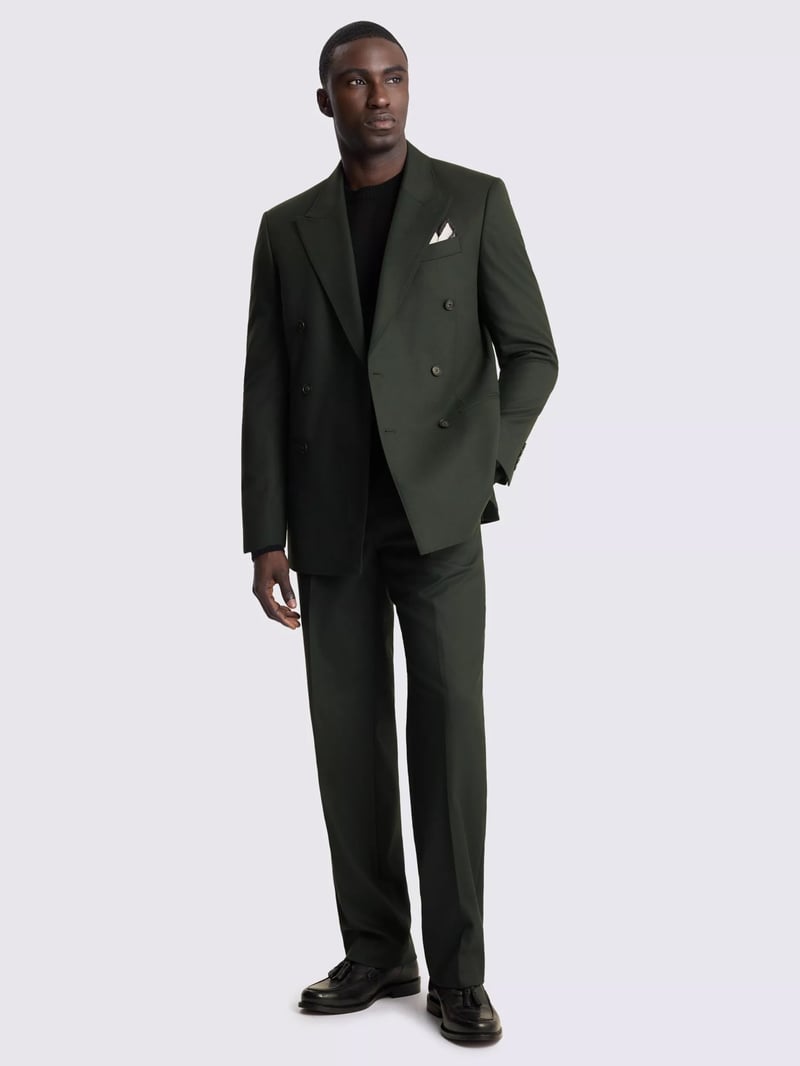 a male model wears a relaxed dark green flannel suit with black t-shirt underneath.