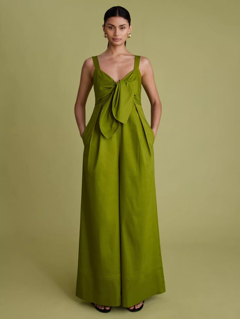 a model wears an olive green wide leg jumpsuit with oversized bow detail on the front.