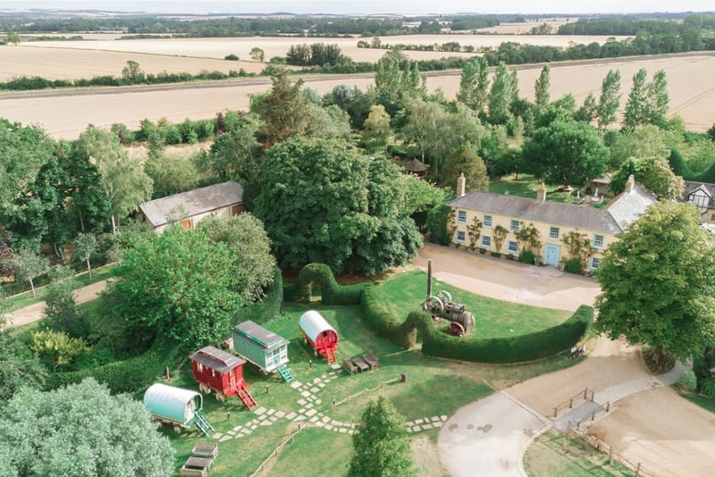 Alt text (95 characters):
aerial view of South Farm's farmhouse, gardens and Romany caravans surrounded by countryside.