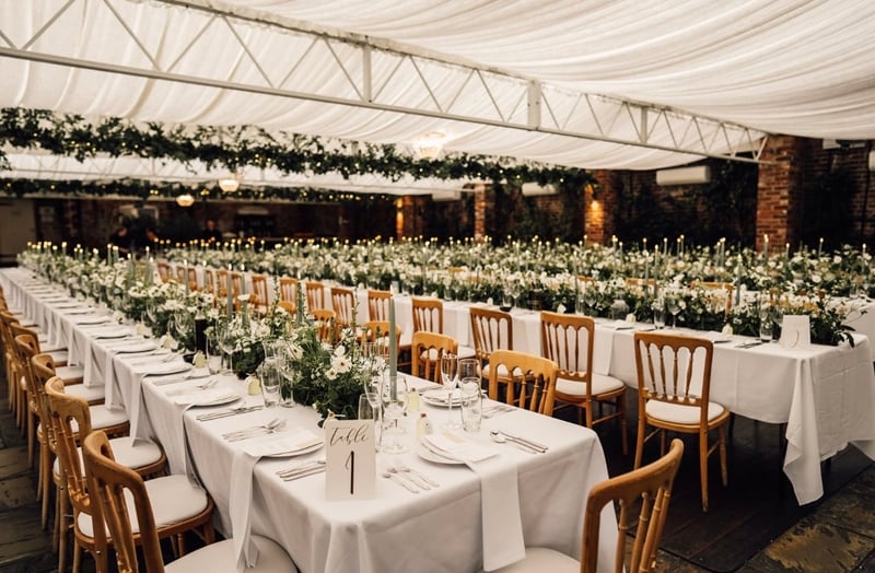interior of a canopy covered orangery set up for a Christmas wedding reception with long tables and low floral tablecentres.
