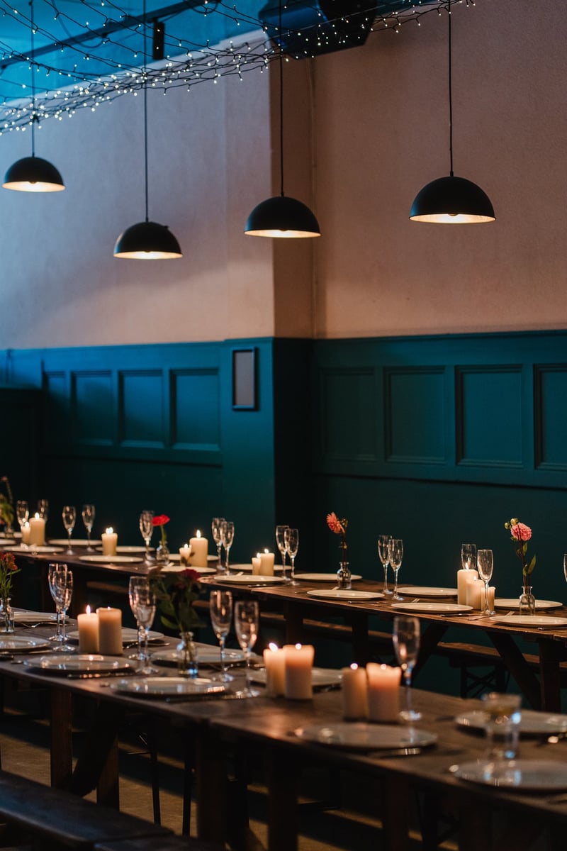 a cool London wedding venue set up for a wedding breakfast with long restaurant-style tables and overhead mood lighting.