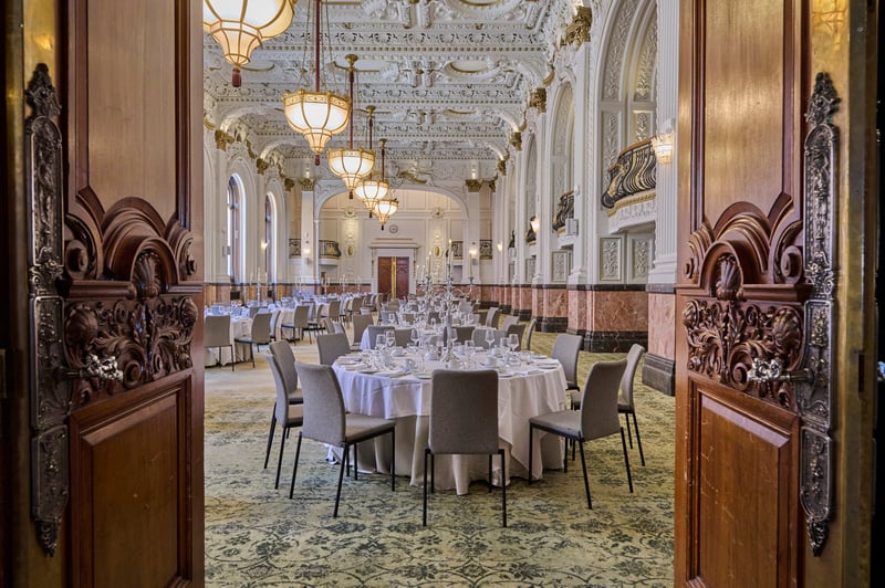 interior of a grand hotel wedding venue set up for a wedding dinner with round tables, marble pillars and art deco interiors.
