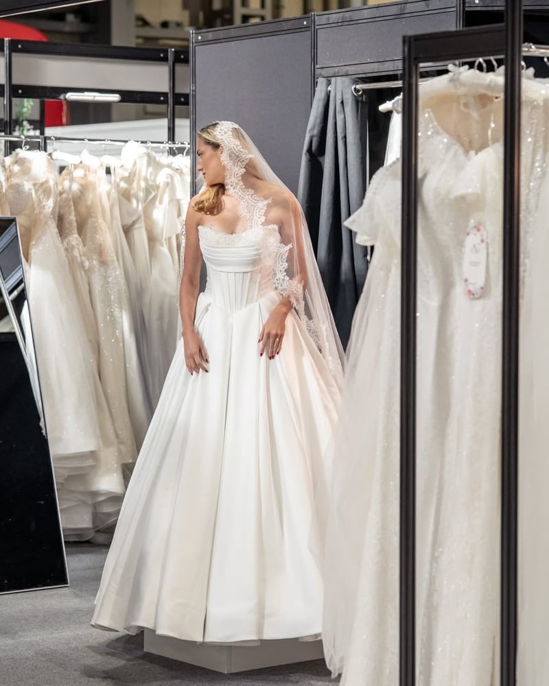 a woman trying on a wedding dress at a wedding show.