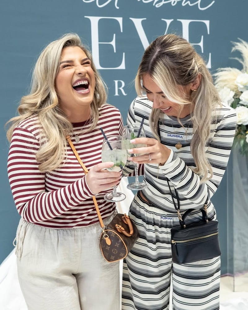 two female friends laughing as they hold cocktails.