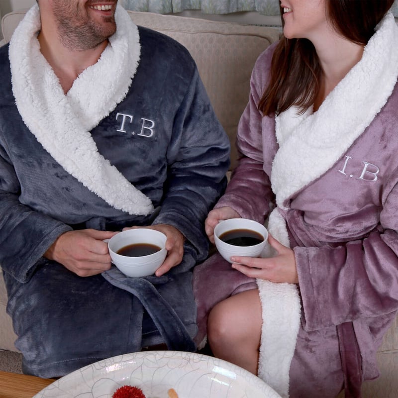a close up of a man and woman wearing matching monogrammed fleece-lined dressing gowns 