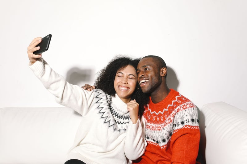 a couple wearing Christmas jumpers taking a selfie.