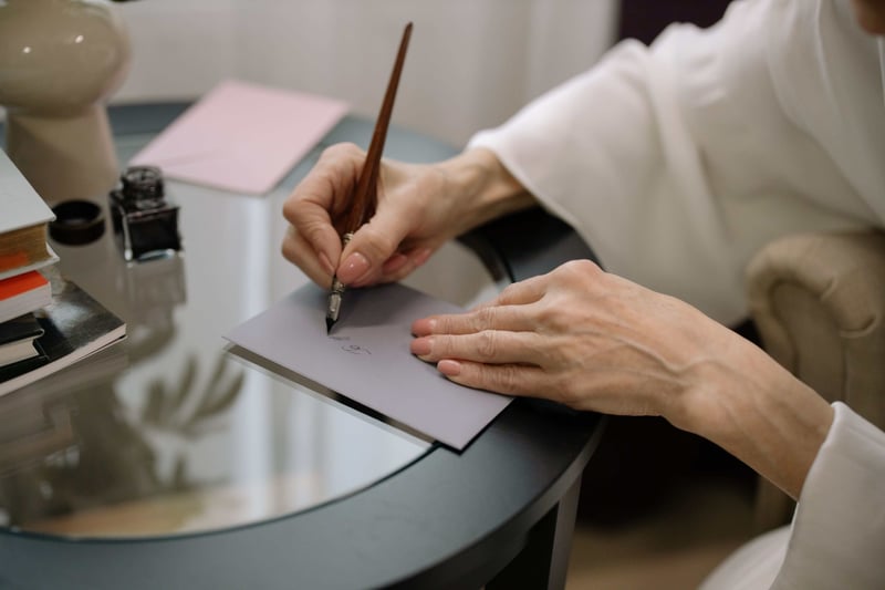 close up of a woman's hand writing on the envelope of a wedding card.