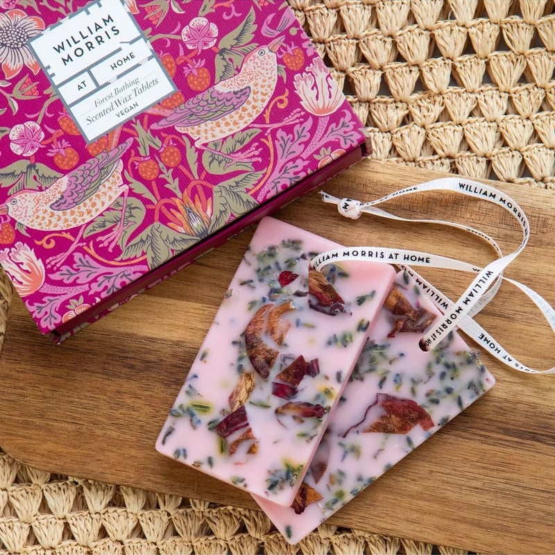 a pair of pink wax tablets on ribbon with dried flower petals next to a pink box with William Morris print.