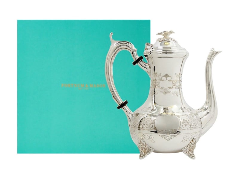 a traditional sterling silver coffee pot next to signature eau de nil Fortnum and Mason box packaging.