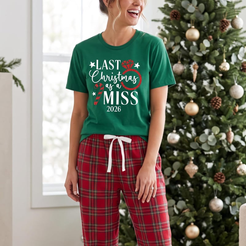 a woman wearing a pair of flannel tartan pyjama bottoms and a green t-shirt with 'Last Christmas as a Miss' in white writing.