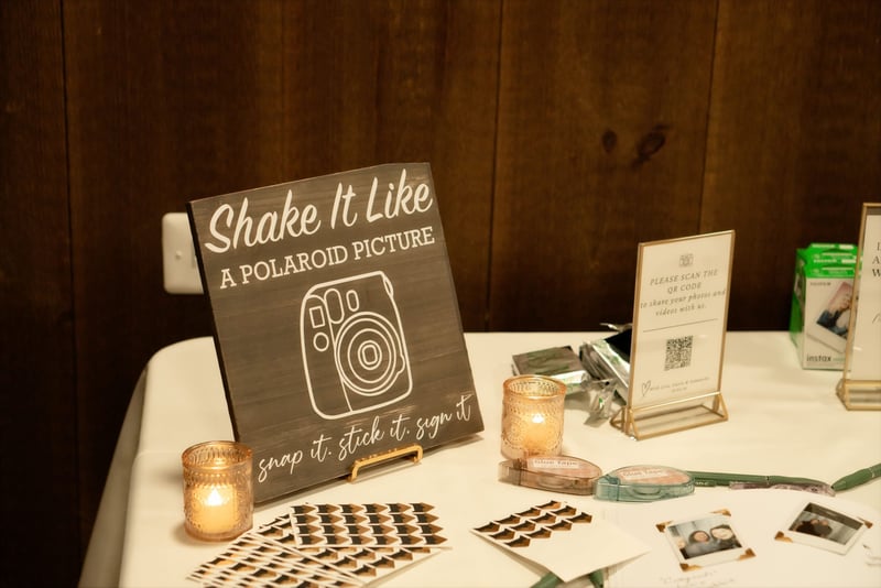 a qr code for wedding photo sign on a table next to a photobooth set up.