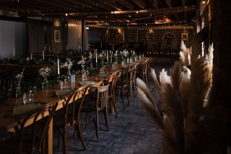 interior of a barn-style beach wedding venue set up with candles and mood lighting for a winter wedding reception.