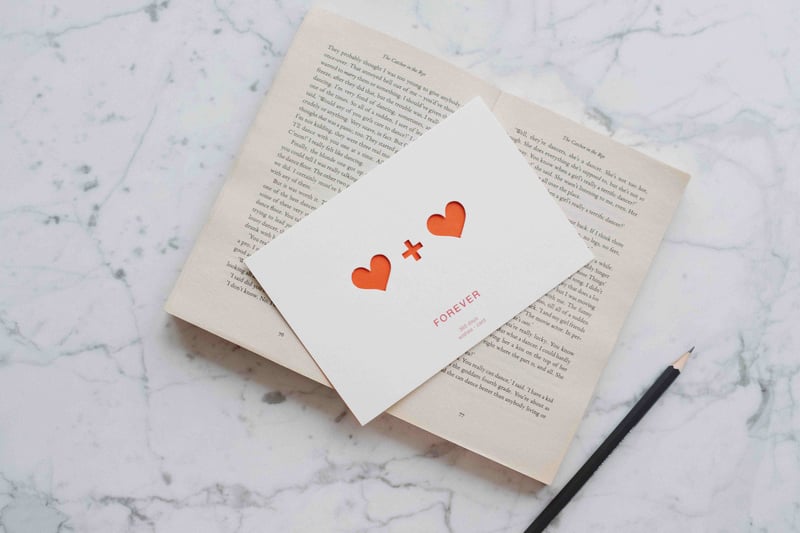 a greetings card with red hearts on it placed on top of an open book.