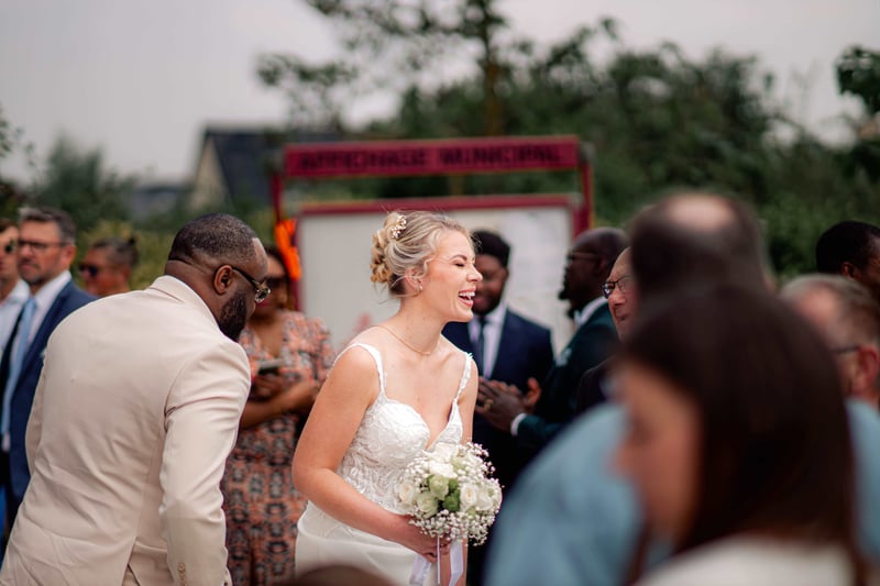 a bride holding her bouquet and laughing with wedding guests.
