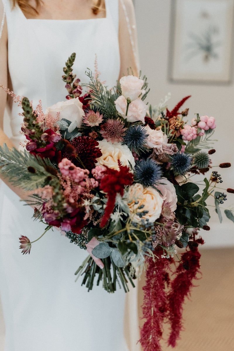 close-up of a winter wedding bouquet with thistles, ranunculus and trailing amaranthus.