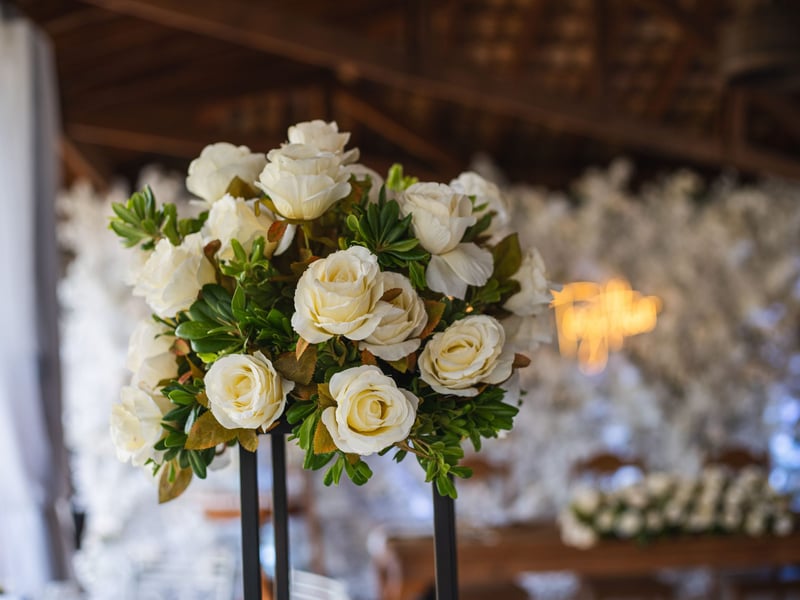 close-up of a tall table centrepiece featuring cream coloured roses.