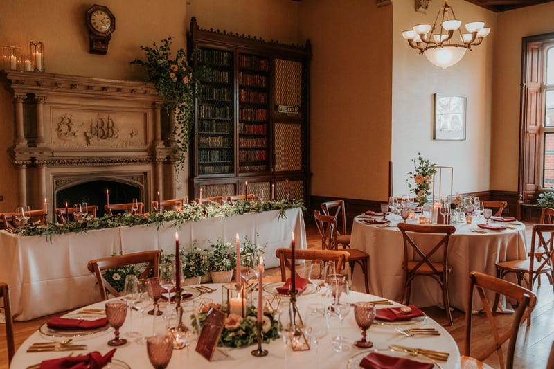 a dining room with statement fireplace and round tables set for a winter wedding reception.
