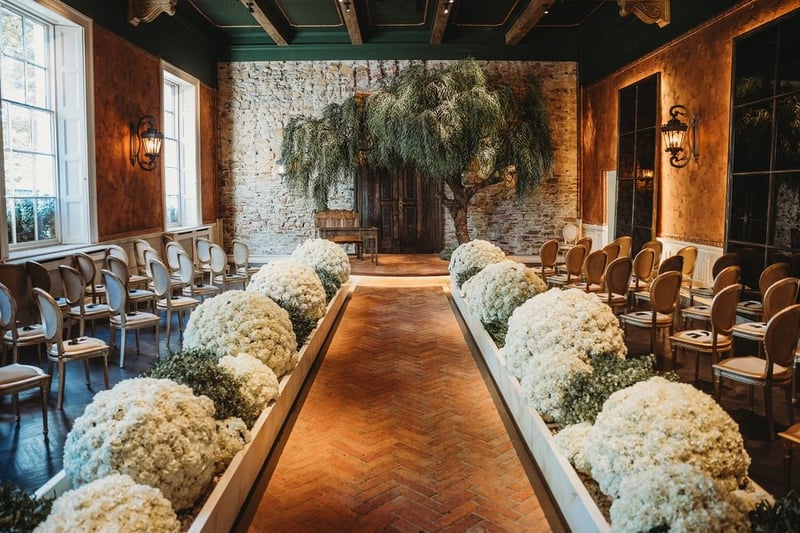 Ceremony room at The Croft with a willow tree, herringbone aisle and white hydrangeas