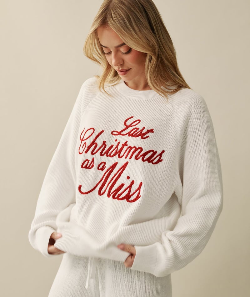 a model wears a white knitted jumper embroidered with Last Christmas as a Miss in red.