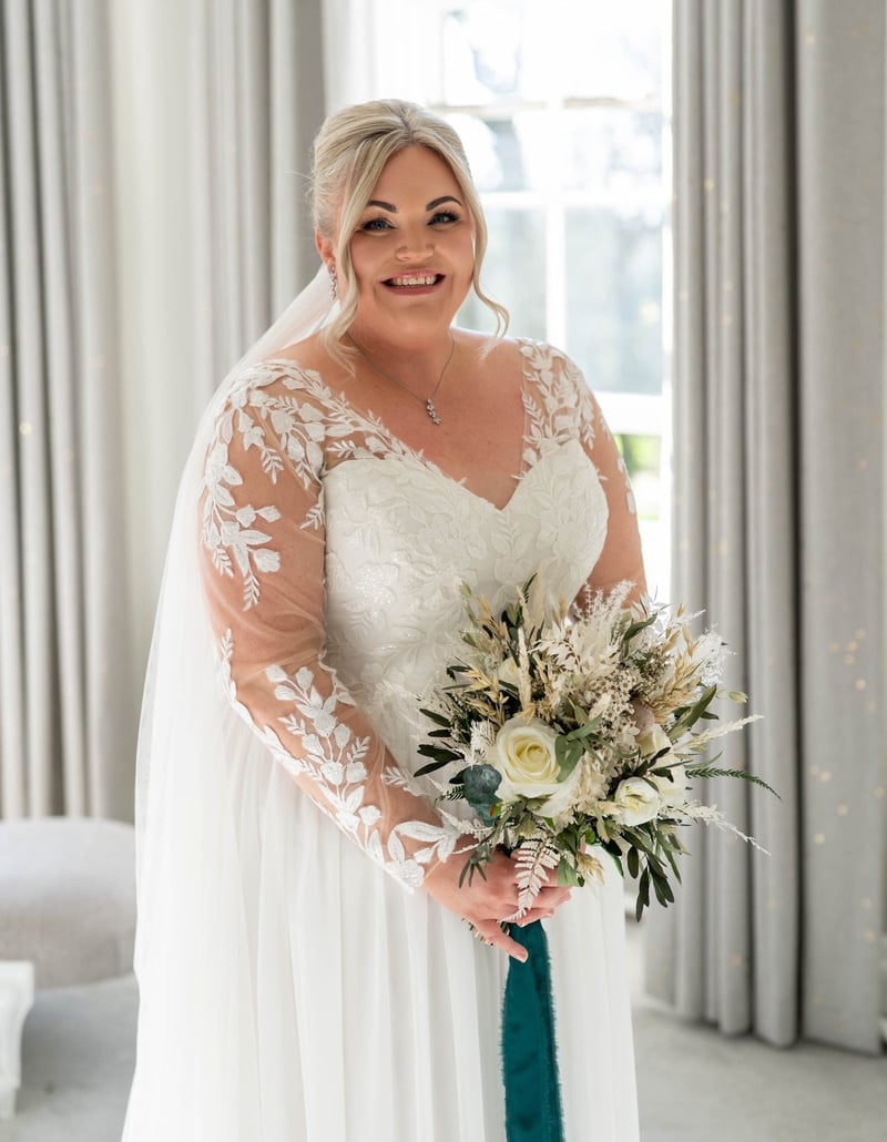a smiling bride carrying a white, green and teal winter wedding bouquet.