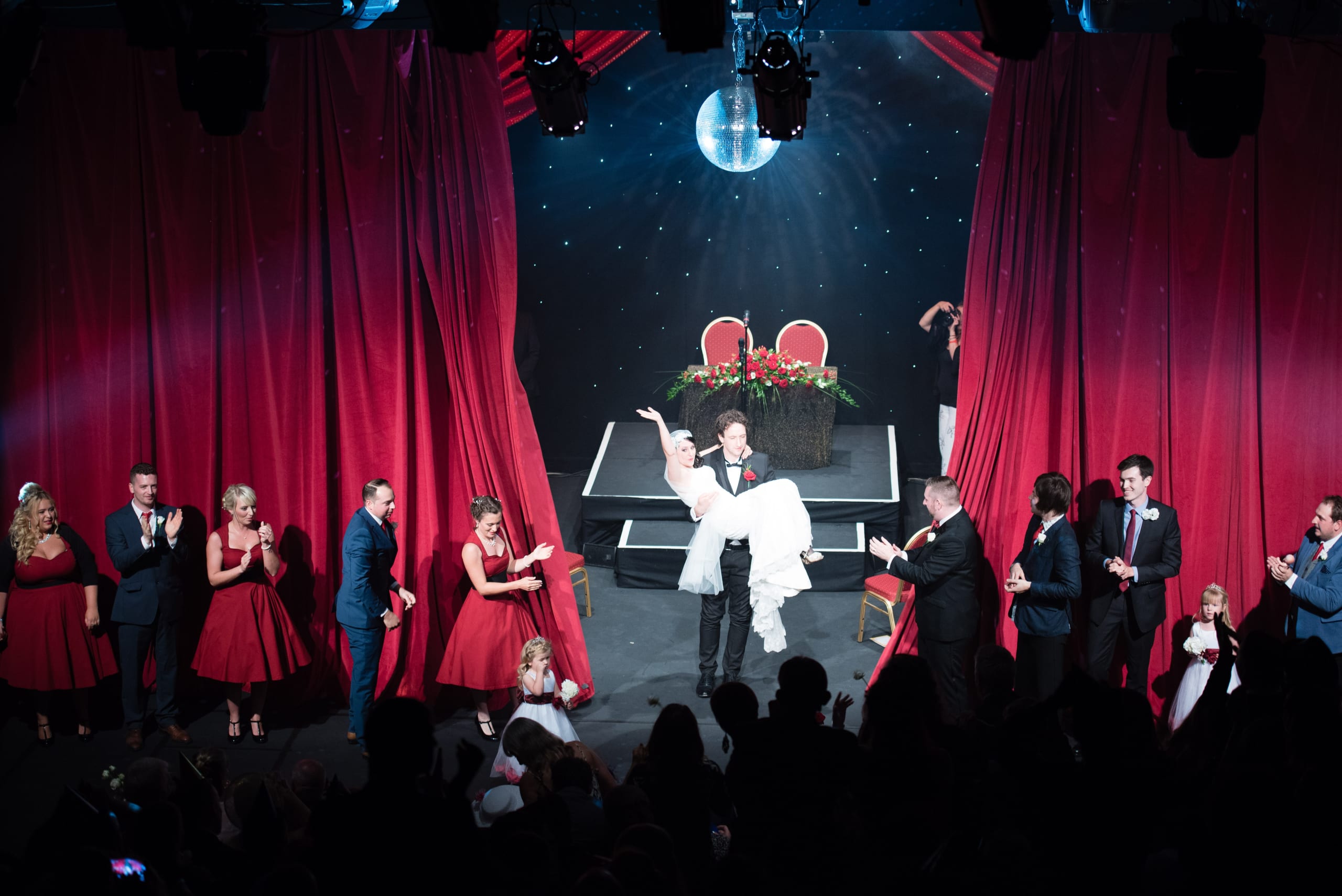 Bridebook.co.uk groom lifts bride up on stage