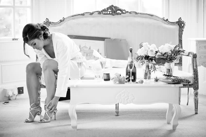 Bridebook.co.uk- bride putting on shoes in bridal suite