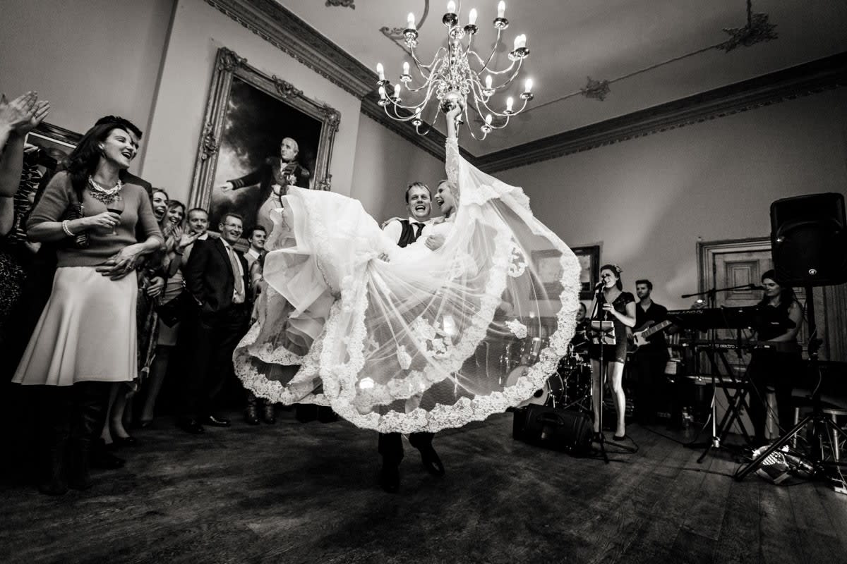 Bridebook.co.uk- groom lifting bride as guests applaud