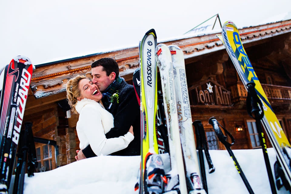 Bridebook.co.uk- bride and groom kissing in front of skiis