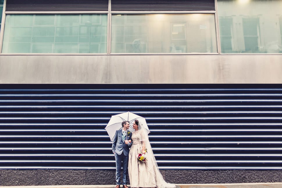 Bridebook.co.uk- bride and groom standing under white umbrella