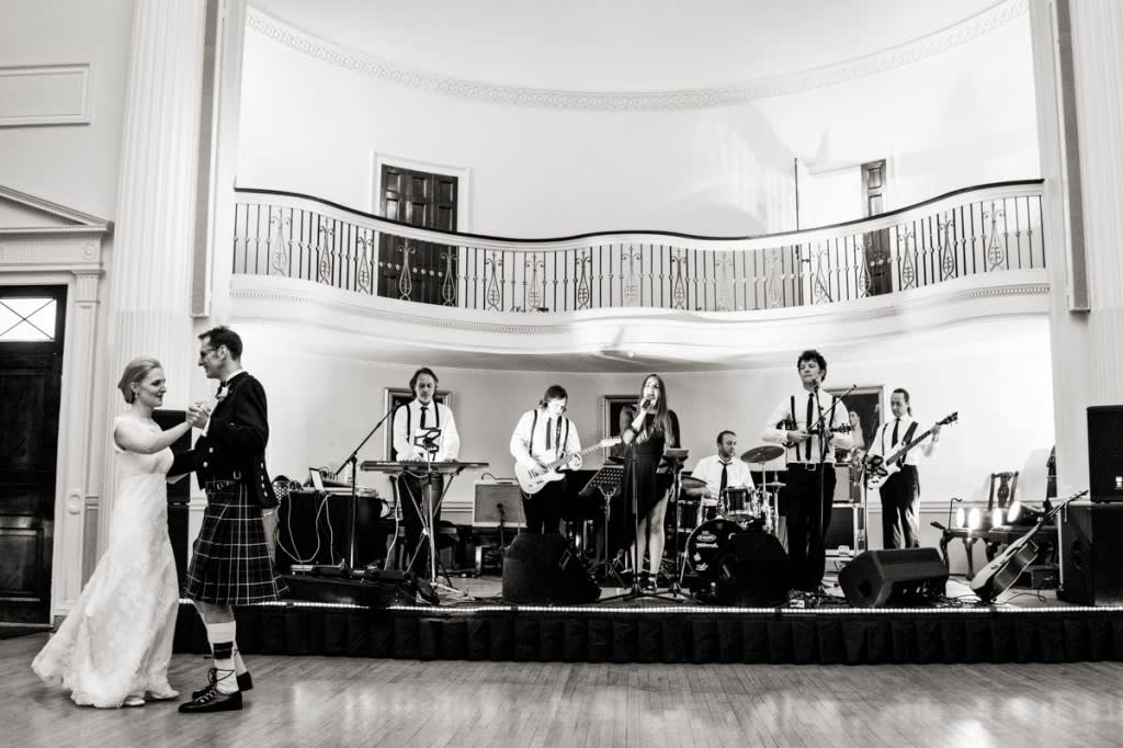 Bridebook.co.uk- bride and groom having their first dance with the band playing in the background