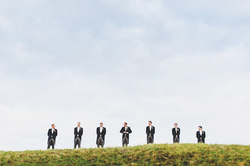 Bridebook.co.uk- groom and ushers standing on a hill against the sky