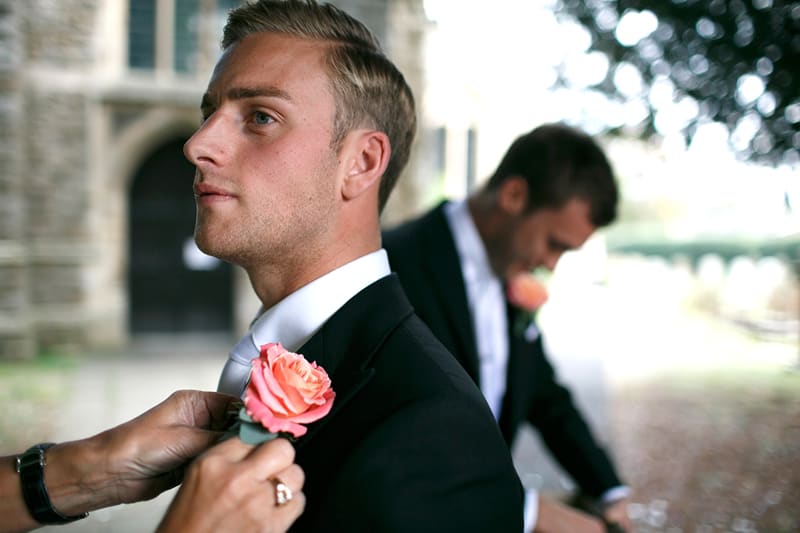 Bridebook.co.uk- groom getting the buttonnaire pinned to the lapel