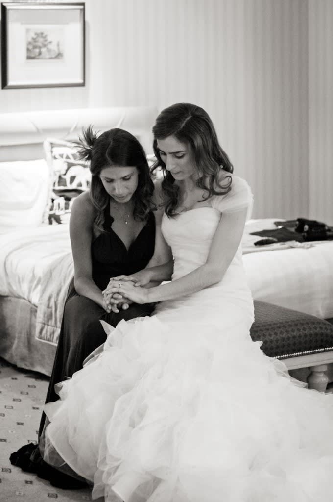 Bridebook.co.uk- bride and maid of honour sitting down and holding hands