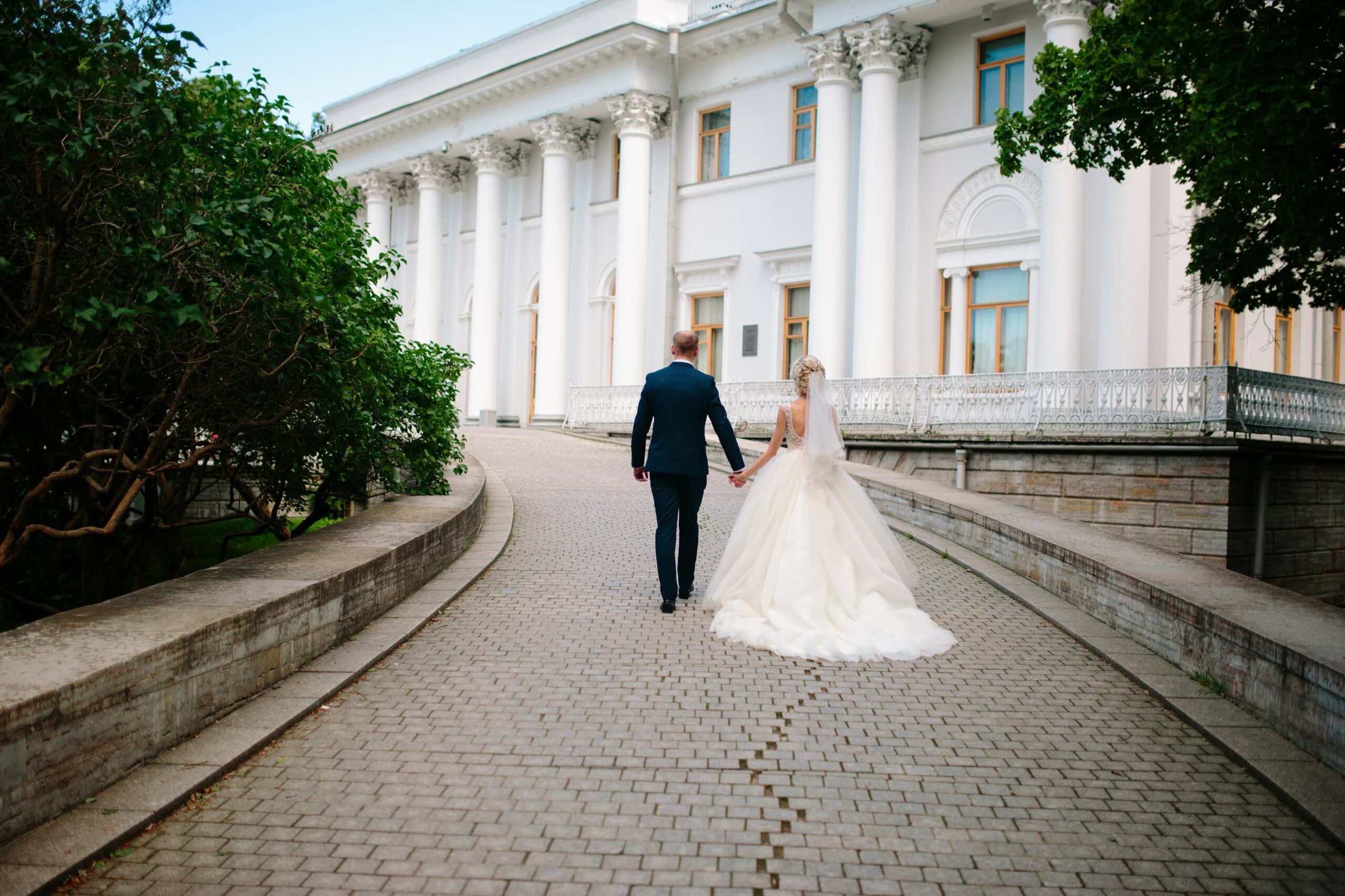 Bridebook.co.uk Bride and groom walking down drive